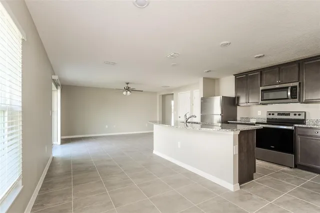 a large kitchen with kitchen island granite countertop a stove top oven a sink a counter top space and cabinets