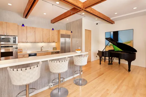 a kitchen with stainless steel appliances kitchen island granite countertop a table chairs in it and wooden floors