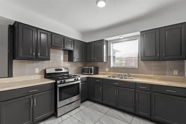 a kitchen with stainless steel appliances a sink stove cabinets and a window