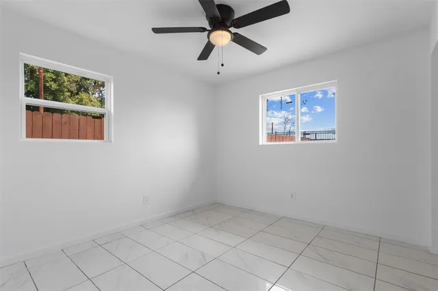 an empty room with windows and fan