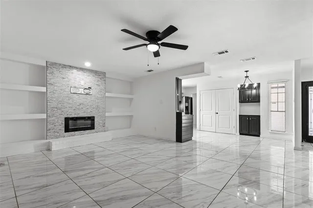a view of a livingroom with a fireplace a ceiling fan and windows