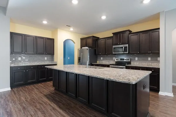 a kitchen with stainless steel appliances granite countertop wooden cabinets a stove top oven a sink and dishwasher