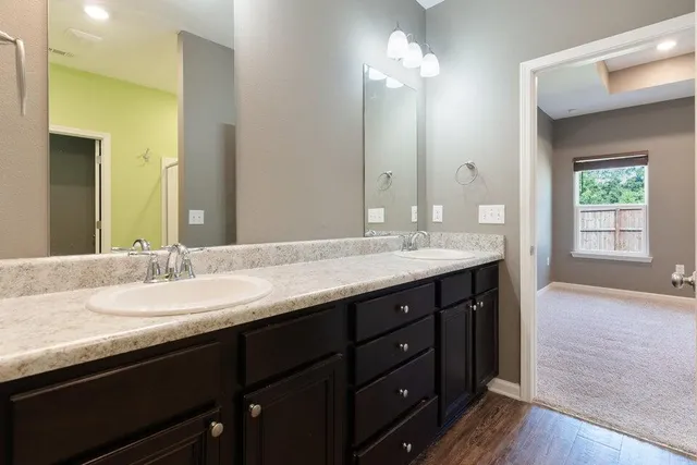 a bathroom with double vanity sinks a vanity a lamp and a mirror