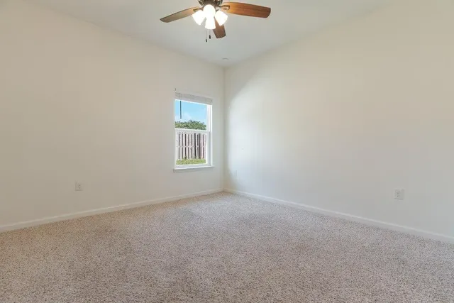 a view of an empty room and chandelier fan
