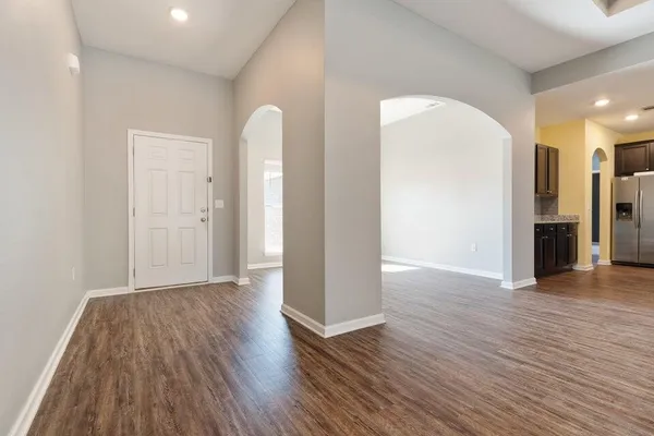 a view of an empty room with wooden floor and a bathroom