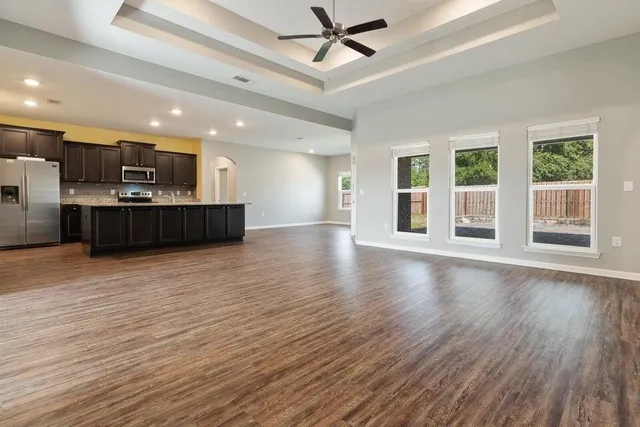 a view of a big room with wooden floor and windows