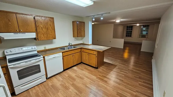 a kitchen with stainless steel appliances granite countertop a sink a stove top oven and wooden floors