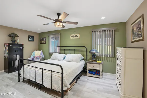 a spacious bedroom with a bed a flat screen tv and dresser