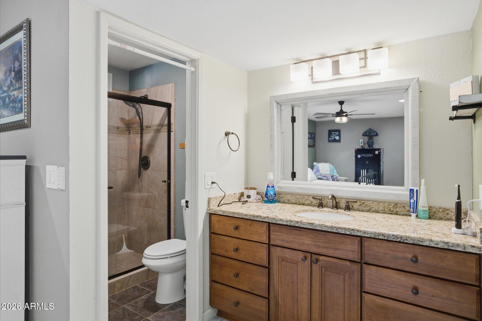 2222 West Maple Drive Phoenix, AZ 85027 - Photo 12 of 32 a bathroom with a granite countertop sink toilet a large mirror a vanity and shower