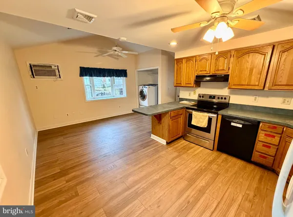 a large kitchen with stainless steel appliances granite countertop a stove a sink dishwasher and a microwave with wooden floor