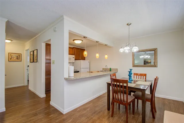 a view of a dining room and livingroom with furniture wooden floor a chandelier
