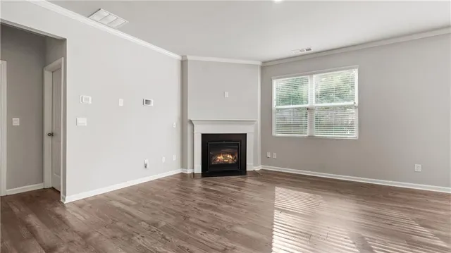 an empty room with wooden floor fireplace and windows