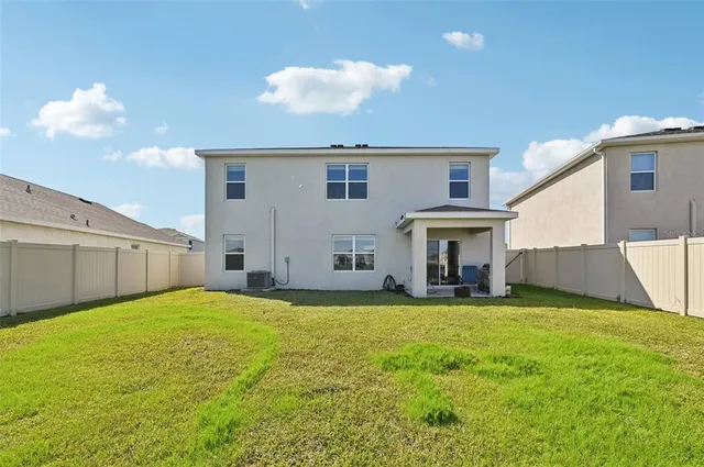 a view of a house with a yard and a large tree