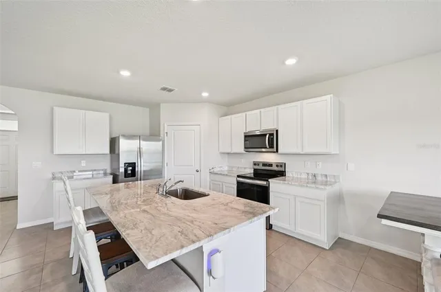 a kitchen with stainless steel appliances kitchen island granite countertop a sink refrigerator and cabinets