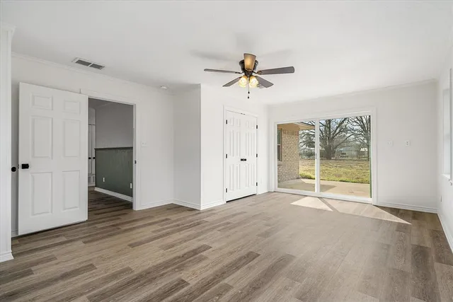 a view of empty room with wooden floor and fan