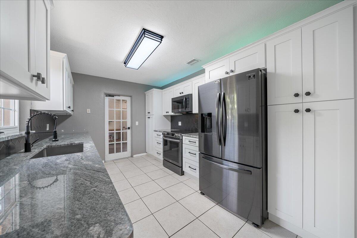 441 Sharon Drive Melbourne, FL 32935 - Photo 7 of 25 a kitchen with stainless steel appliances granite countertop a refrigerator a stove and a sink