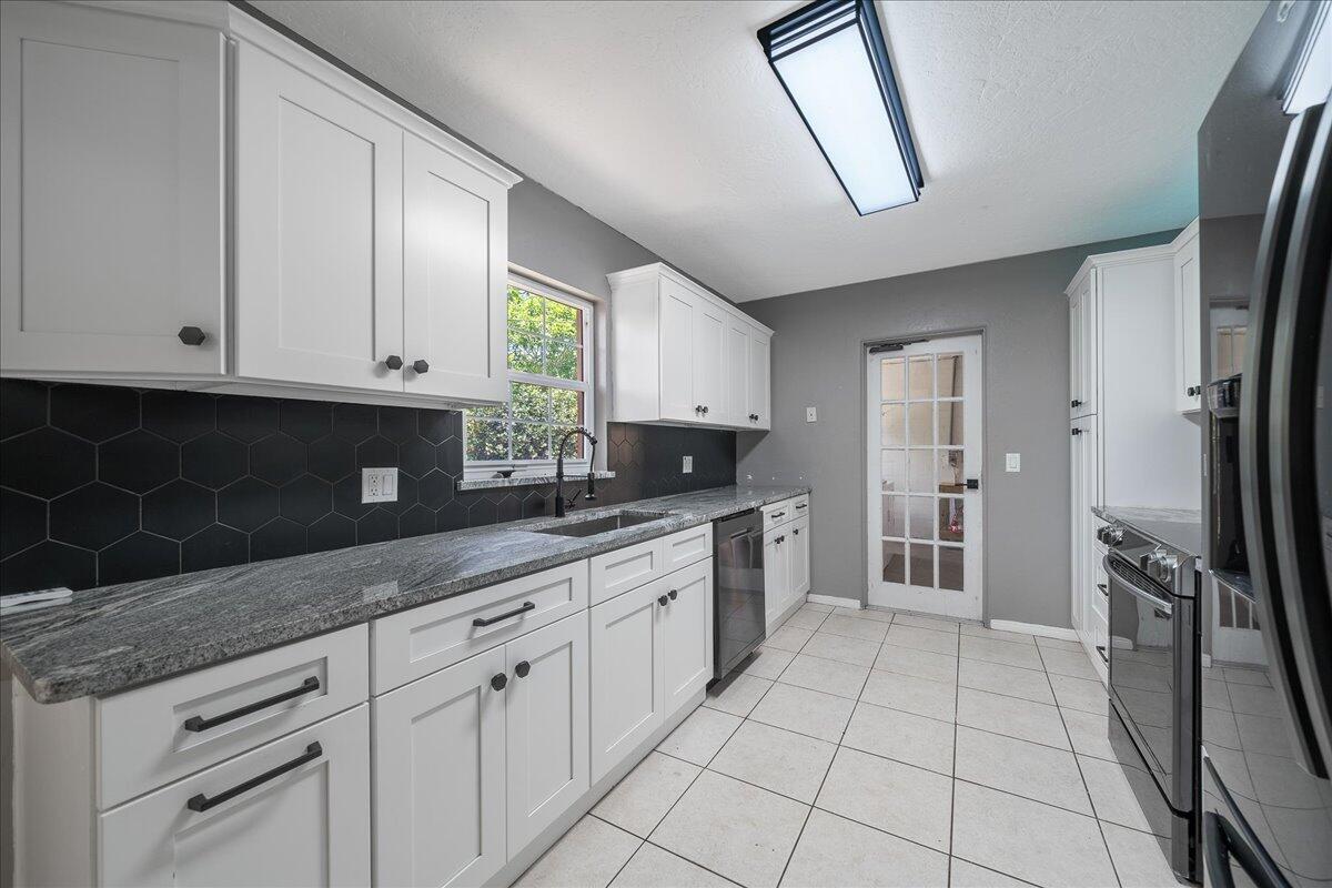 441 Sharon Drive Melbourne, FL 32935 - Photo 8 of 25 a kitchen with granite countertop a stove a sink and a refrigerator