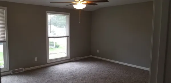 an empty room with windows and fan