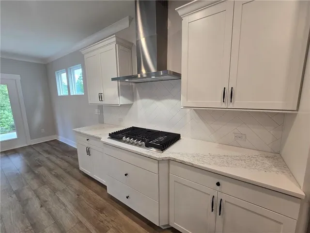 a kitchen with white cabinets and wooden floor