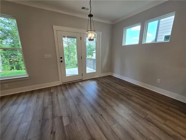 an empty room with wooden floor fireplace and windows