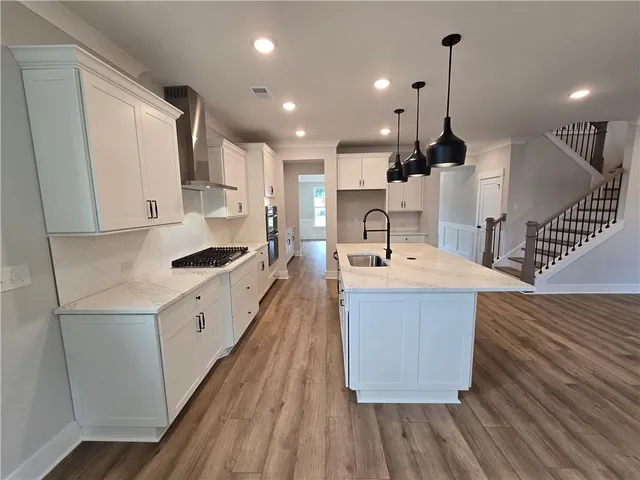 a kitchen with kitchen island a stove a sink and a wooden floor