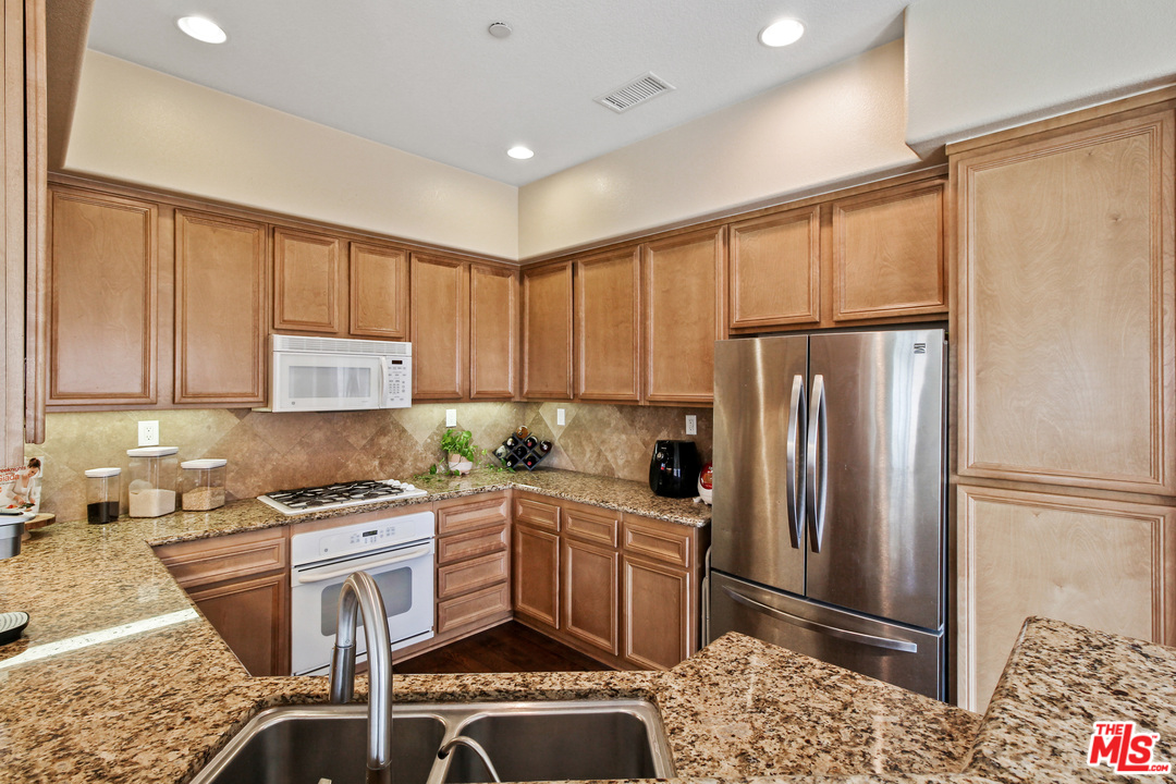 4153 Paredo Way, Unit A Simi Valley, CA 93063 - Photo 8 of 33 a kitchen with stainless steel appliances granite countertop a refrigerator sink and cabinets