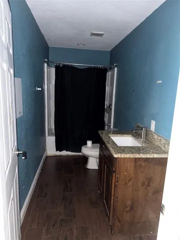 a bathroom with a granite countertop sink a toilet a mirror and shower curtain