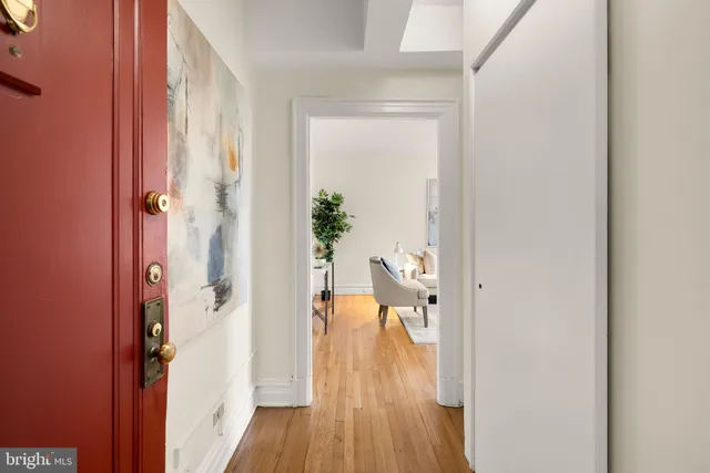 a view of a hallway with wooden floor and a livingroom