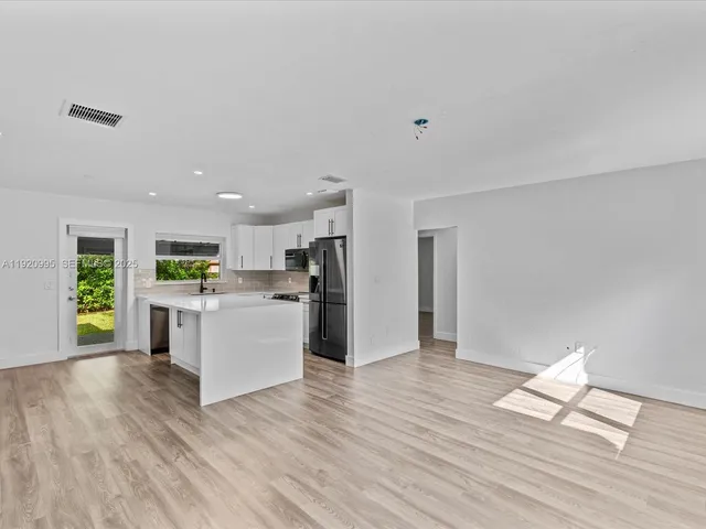 a view of kitchen with refrigerator cabinets and wooden floor