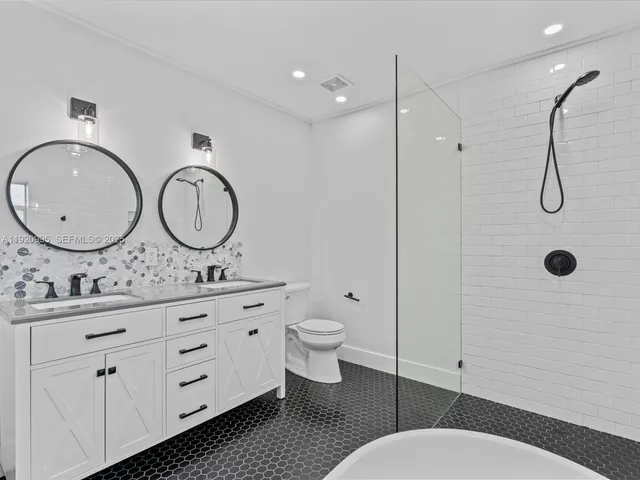 a bathroom with a toilet a sink a mirror a vanity and shower