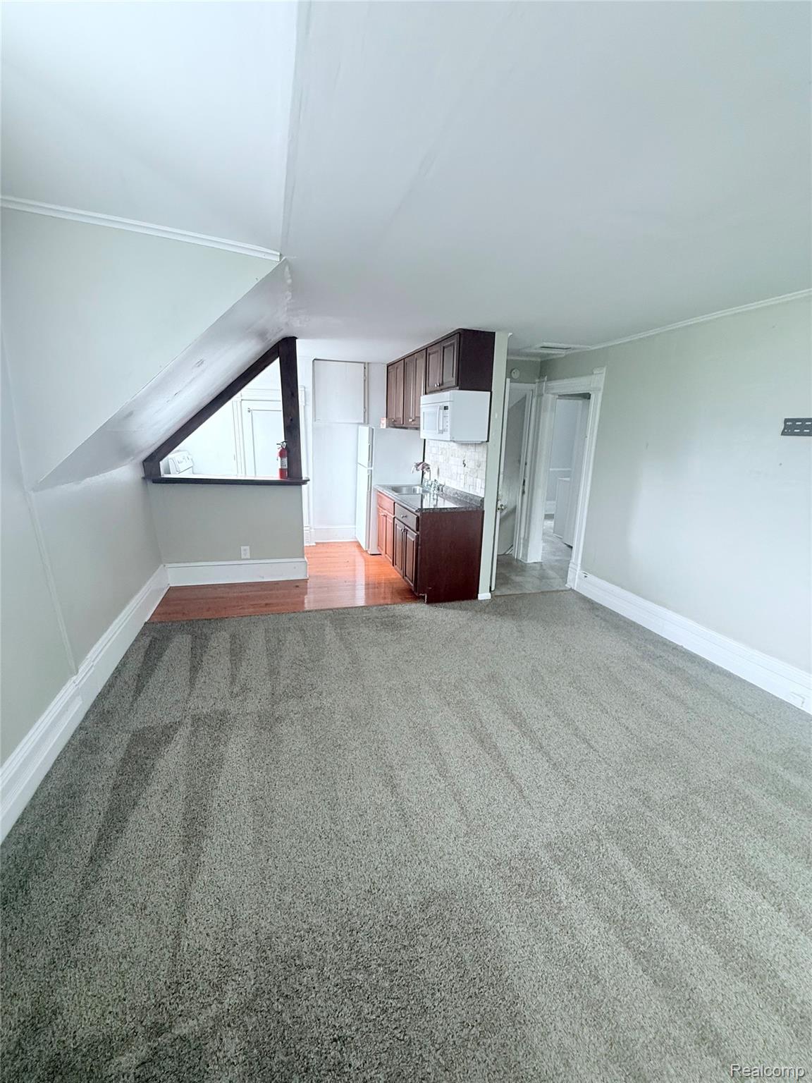415 Coutant Street, Unit B Flushing, MI 48433 - Photo 10 of 11 Unfurnished living room with light carpet, ornamental molding, and lofted ceiling