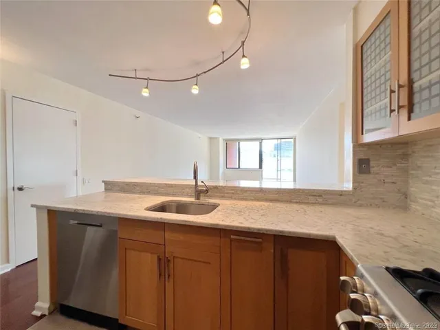 a kitchen with granite countertop kitchen island a sink and a stove with wooden floors