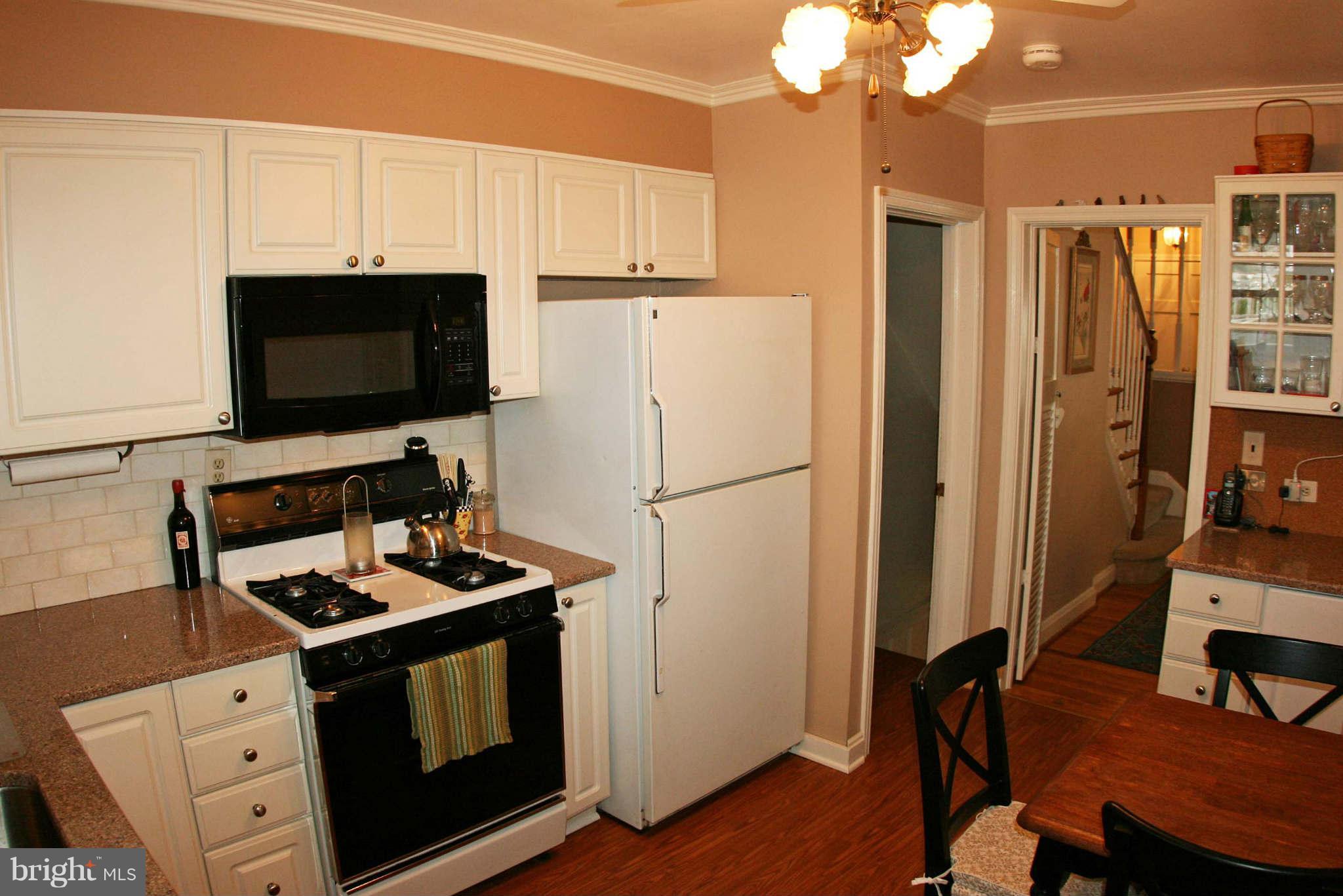 1835 Glen Ridge Road Baltimore, MD 21286 - Photo 9 of 30 a kitchen with stainless steel appliances a stove a refrigerator and a dining table with wooden floor
