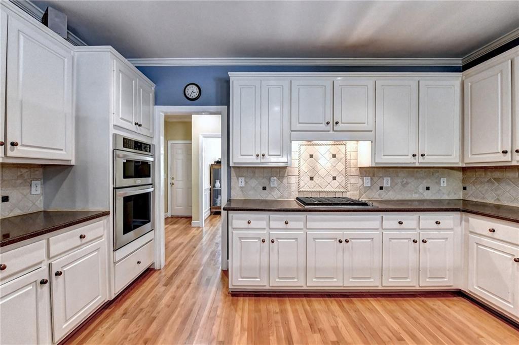 1595 Chadberry Way Lawrenceville, GA 30043 - Photo 5 of 47 a kitchen with granite countertop a wooden floors white cabinets and white appliances