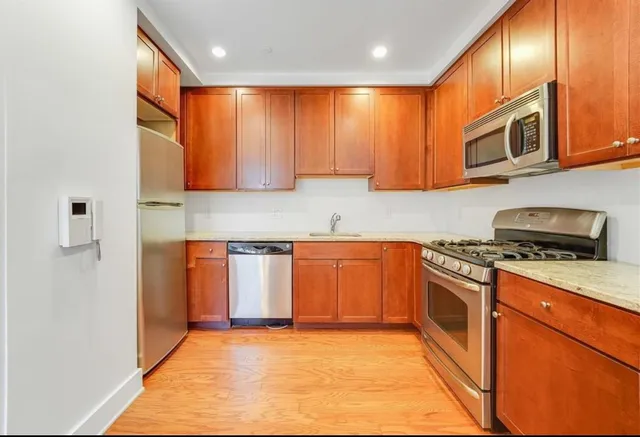 a kitchen with stainless steel appliances granite countertop wooden cabinets a stove top oven a sink and dishwasher