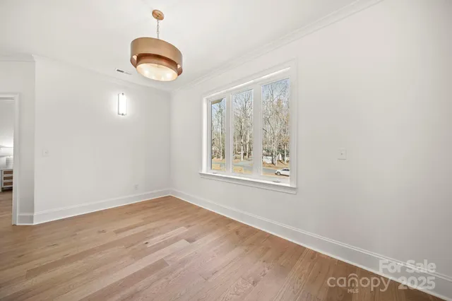an empty room with wooden floor chandelier and windows