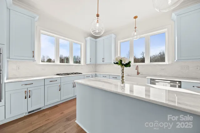 a kitchen with stainless steel appliances granite countertop a sink a stove and a wooden floors