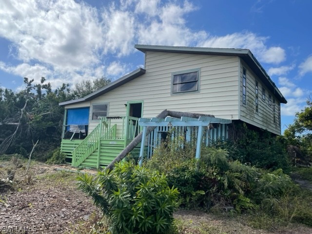 6670 Sun Rise Lane Bokeelia, FL 33922 - Photo 2 of 13 a backyard of a house with plants and barbeque oven