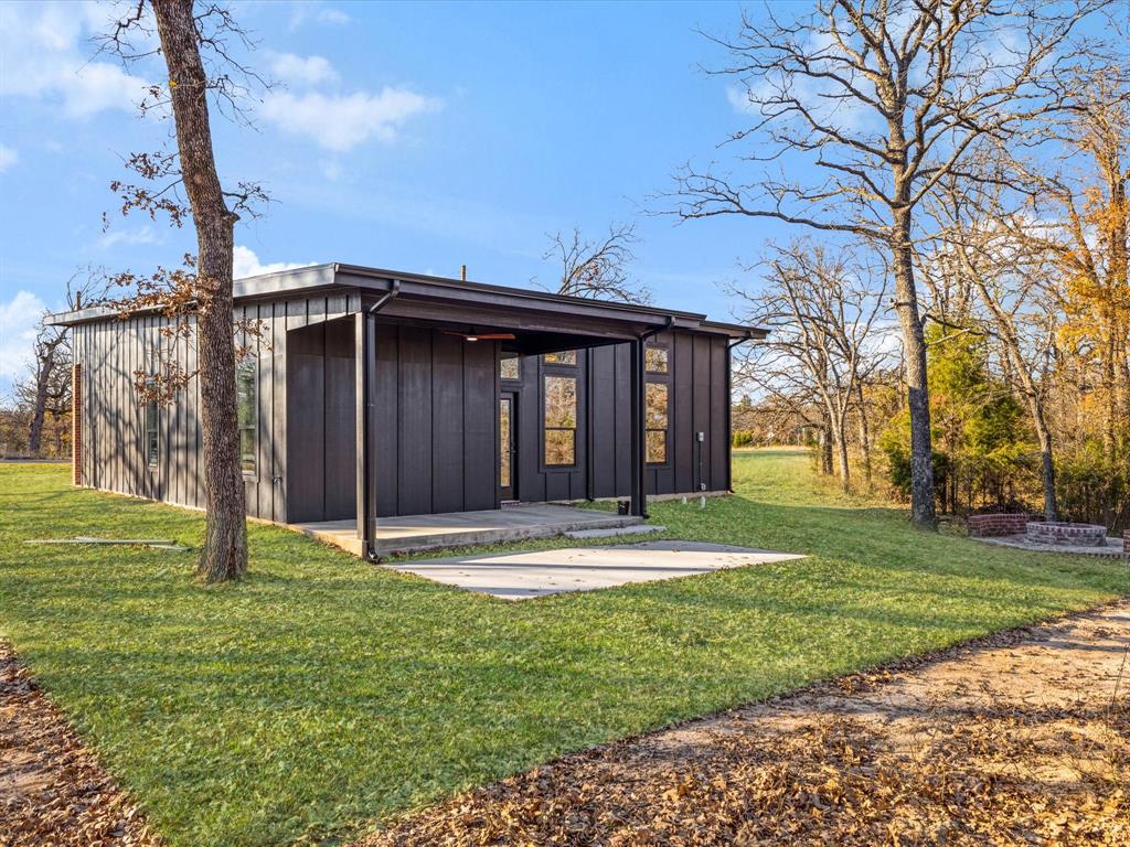 5018 Point La Vista Road Malakoff, TX 75148 - Photo 23 of 32 Rear view of house featuring board and batten siding, a patio area, and a lawn