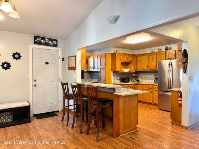 a kitchen with stainless steel appliances kitchen island granite countertop a table chairs and a refrigerator