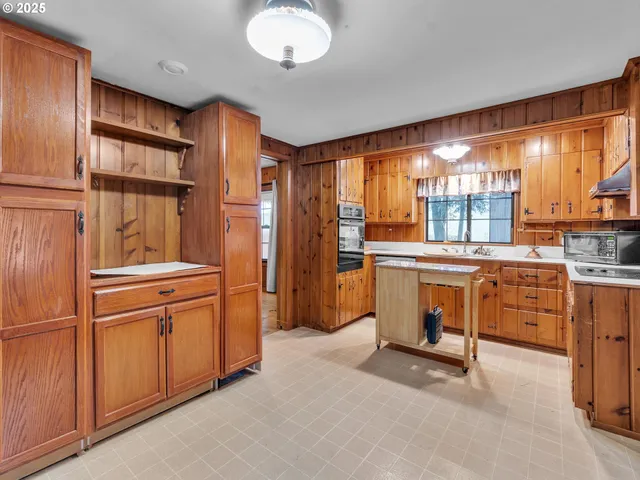 a kitchen with granite countertop a refrigerator stove top oven dining table and chairs