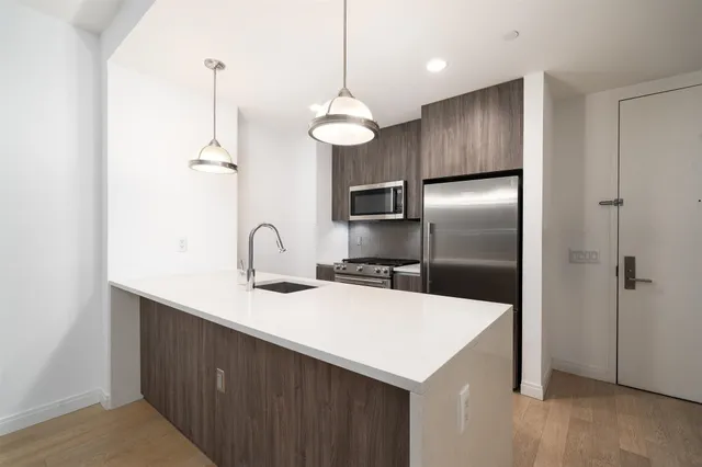 a kitchen with kitchen island a refrigerator and a sink