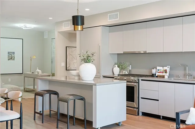 a kitchen view with stainless steel appliances kitchen island granite countertop a table chairs and a refrigerator