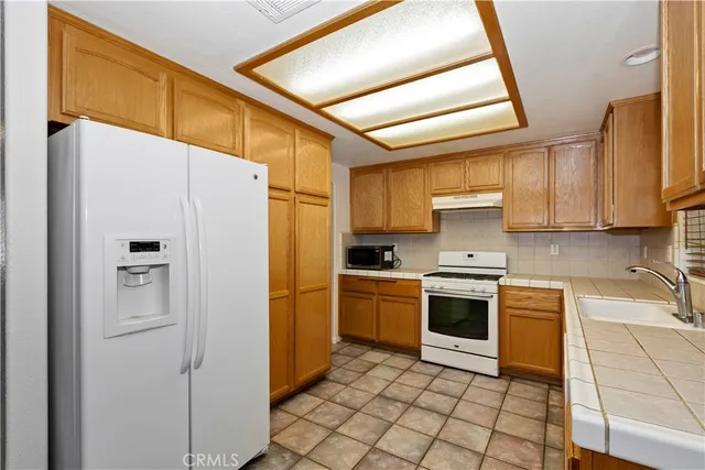 a kitchen with stainless steel appliances granite countertop a refrigerator a sink dishwasher a stove with wooden cabinets