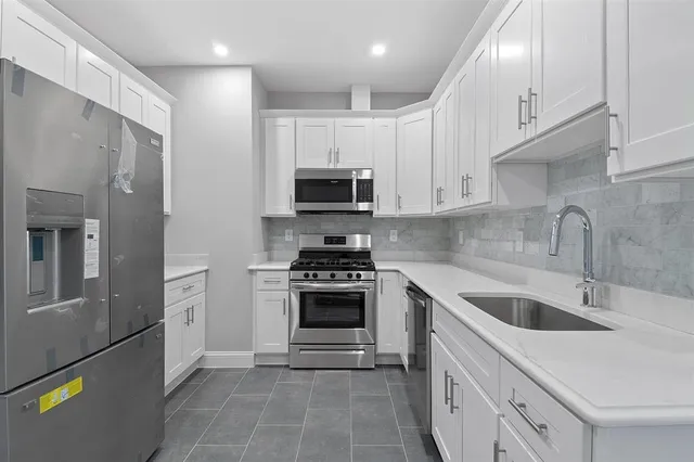a kitchen with stainless steel appliances granite countertop a sink and a refrigerator