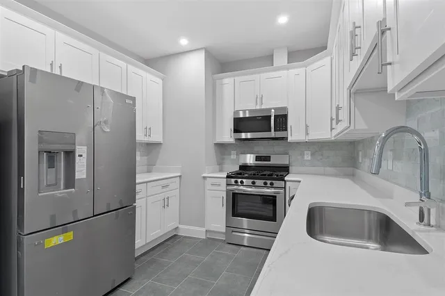 a kitchen with stainless steel appliances granite countertop a refrigerator sink and stove