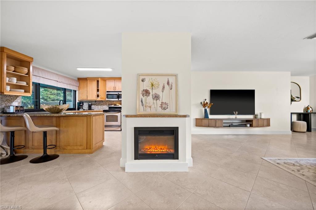 472 Palm River Boulevard Naples, FL 34110 - Photo 13 of 50 a living room with furniture a fireplace and a flat screen tv