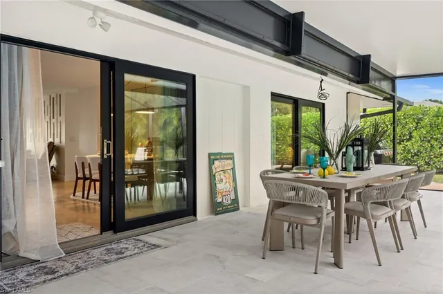 a patio with a table and chairs and potted plants