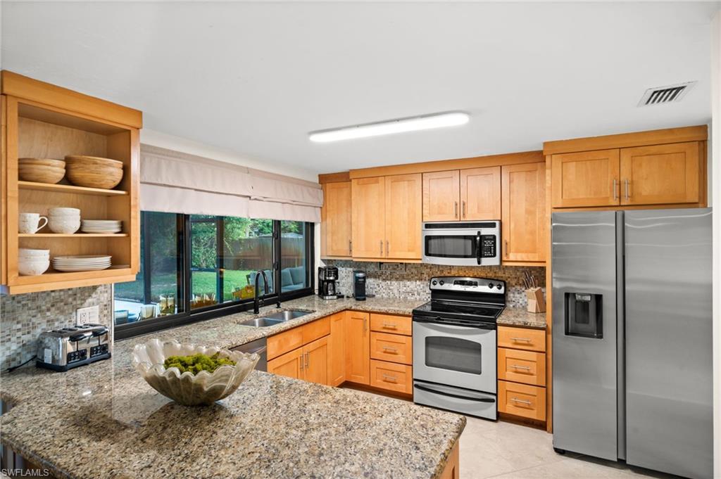 472 Palm River Boulevard Naples, FL 34110 - Photo 3 of 50 a kitchen with stainless steel appliances a stove sink and microwave