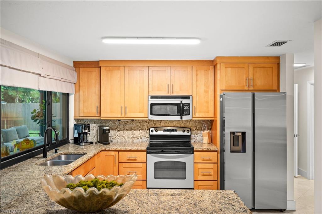 472 Palm River Boulevard Naples, FL 34110 - Photo 7 of 50 a kitchen with stainless steel appliances granite countertop a stove refrigerator and microwave